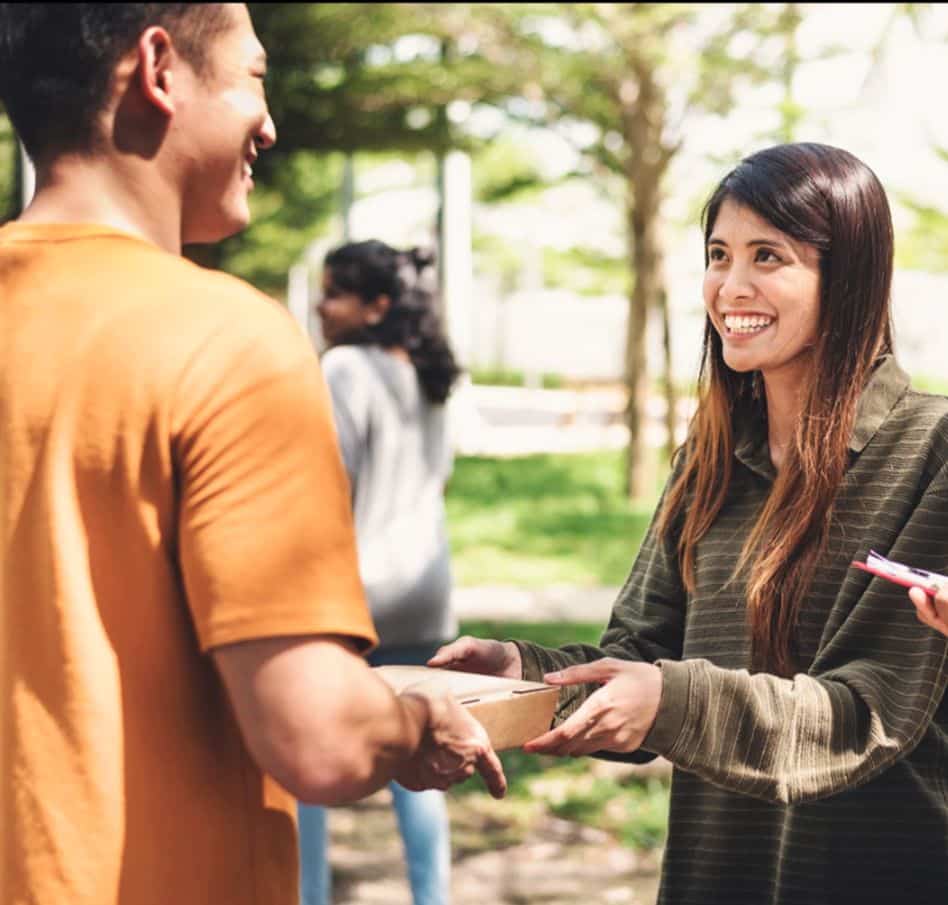 Women smiling at a man as he hands her a clipboard.