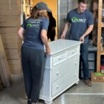 Two people carrying a dresser.