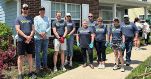Group of people of smiling for a picture standing in front of a house.
